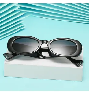 Détail de lunettes de soleil ovales noires vintage avec monture épaisse sur fond bleu