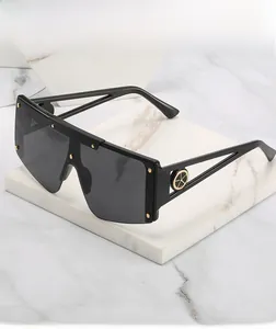 Detail of shield sunglasses with gold studs on black frame and ornate metallic temples