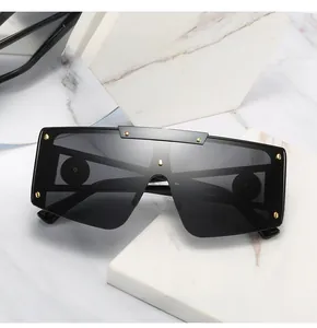 Detail of oversized shield sunglasses with gold rivets on a minimalist marble block