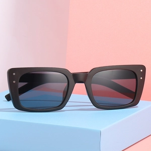 Lunettes de soleil carrées noires avec rivets argentés sur fond géométrique moderne