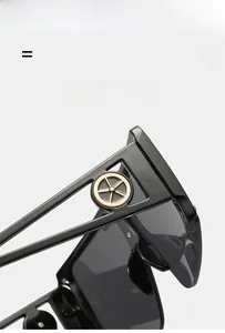 Detail of black oversized sunglasses frame with a circular golden metal logo on the temple