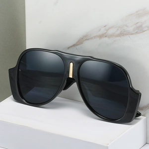 Oversized black square sunglasses with luxury gold bridge detail on marble background