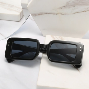 Retro black rectangular sunglasses with silver rivets on marble stone background