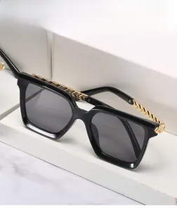 Detail of square sunglasses with black frame and decorative gold chain on the temples