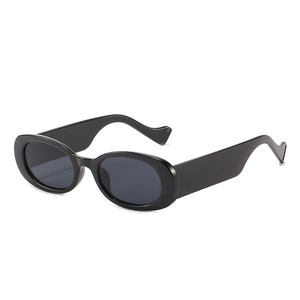Lunettes de soleil ovales noires pour femmes avec branches ondulées sur fond blanc neutre