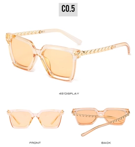 Macro detail of square orange sunglasses showing gold textured metal temples and frames