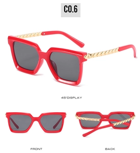 Detail view of bold red square sunglasses with textured gold metal temples and gray lenses