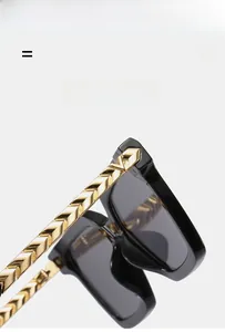 Detail of luxury sunglasses with black frames and gold metal chevron-patterned temples