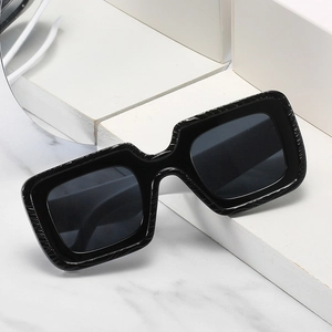 Lunettes de soleil carrées noires avec monture texturée sur socle en marbre