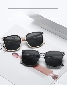 Dettaglio di occhiali da sole quadrati color crema e grigio su rivista di moda