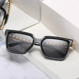 Classic black square sunglasses with textured gold metal temples on marble background
