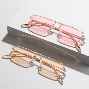 Vintage gold metal narrow frame sunglasses with pink and orange lenses in a studio setting