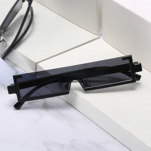 Black pixelated square sunglasses with jagged edges on a white marble display block
