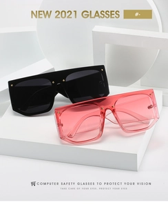 Detail of oversized square sunglasses with gold rivet accents on geometric display stand