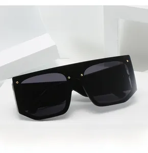 Detail of oversized flat top sunglasses featuring golden rivets on a black frame