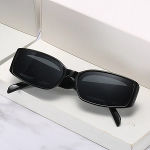 Lunettes de soleil rectangulaires noires à monture épaisse sur un socle en marbre blanc