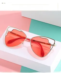 Detail view of cat eye sunglasses with gold metal frame and red gradient lenses