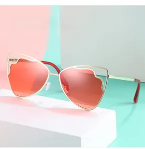 Detailed close-up of cat-eye sunglasses with gold metal frame and red tinted lenses