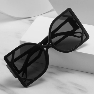 Occhiali da sole neri oversize con montatura geometrica traforata su marmo elegante