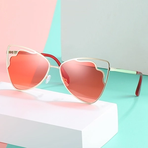 Cat eye sunglasses with wave-shaped gold metal frame and red lenses on geometric blocks