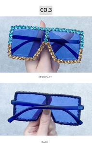 Detail view of oversized sunglasses with blue lenses and gradient rhinestone frame