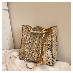 Detailed close-up of woven mesh texture and fringe tassel on straw shoulder tote bag