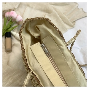 Close-up of woven straw bag interior with beige fabric lining and secure silver zipper