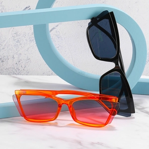Cat eye sunglasses with orange and black frames on a marble background with artistic decor