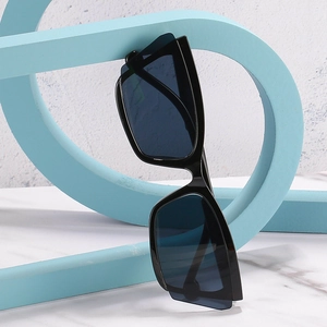 Trendy cat eye sunglasses with thick black frames displayed on a blue geometric prop
