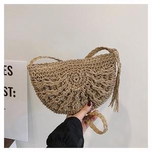 Detail of hollow-out straw crossbody bag featuring half-moon shape and side fringe tassel