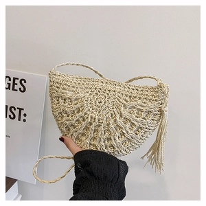 Detailed macro view of beige straw woven shoulder bag with intricate crochet pattern and tassels