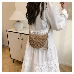 Detail of a handmade hollow-out woven straw crossbody bag with wave texture and long tassels