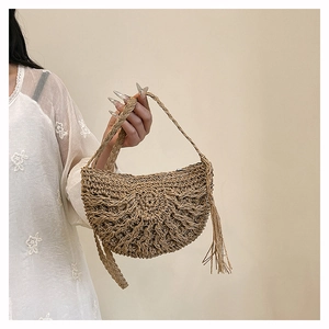 Detail of hand-woven straw shoulder bag with hollow texture and elegant tassel accent