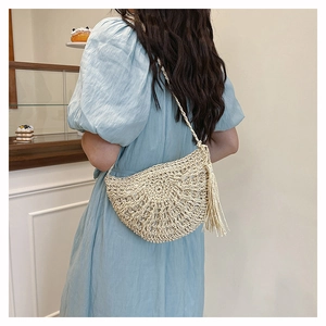 Straw hollow-out crossbody bag with tassels shown on a model in blue dress