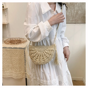 Detail of hollow woven straw bag with stylish long tassel fringe on summer dress