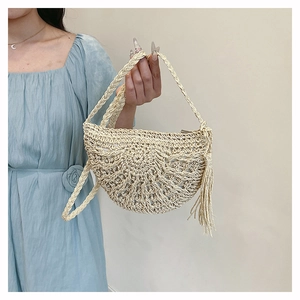 Detail of beige straw handbag featuring intricate hollow crochet patterns and long side tassels