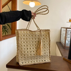 Handwoven straw tote bag with geometric cutouts and tassels for summer fashion