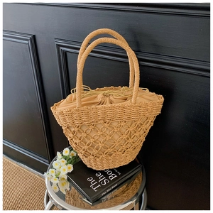 Close-up of a woven straw handbag with hollow diamond pattern and drawstring liner