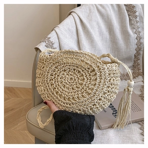 Detailed view of handmade woven round bag with bohemian tassels and wooden beads