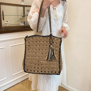 Handcrafted woven straw tote bag with brown wave pattern and fringe tassel charm detail
