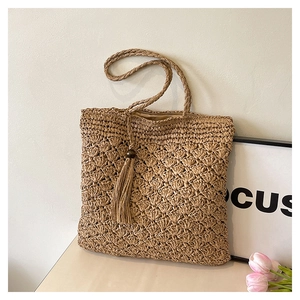 Detail of hand-woven straw bag featuring fan-shaped texture and wood bead tassel charm