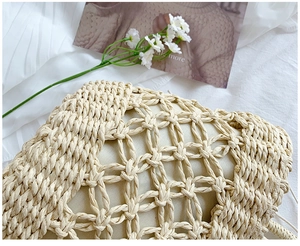 Detail of hollow mesh woven straw bag with beige inner lining on white textured fabric