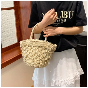 Detail of beige straw bucket bag featuring drawstring lining and woven texture