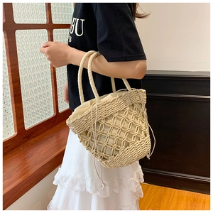 Detail of hand-woven straw bucket bag with drawstring liner and dual handles for summer