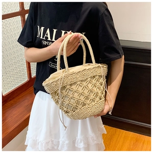 Detail of beige straw handbag featuring diamond hollow pattern and drawstring liner