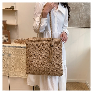 Detail shot of handwoven straw tote bag with fan-shaped textures and tassel wood bead accent