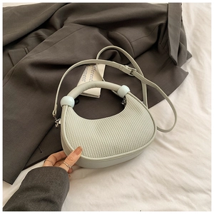 Detail of mint green crescent bag with vertical pleats and blue bead decorative handle