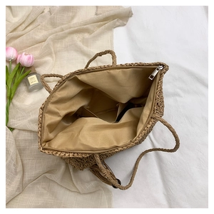 Detailed view of straw woven bag interior with fabric lining and secure metal zipper