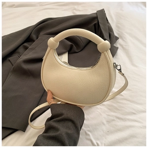 Chic cream-colored half-moon crossbody bag with pebble texture and knot handle detail