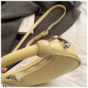 Detail shot of light yellow crescent bag showing lychee texture and silver zipper